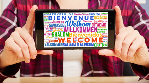 Smartphone mit Willkommensbotschaft Ein Smartphone zeigt ein Bild mit "Willkommen" in verschiedenen Sprachen